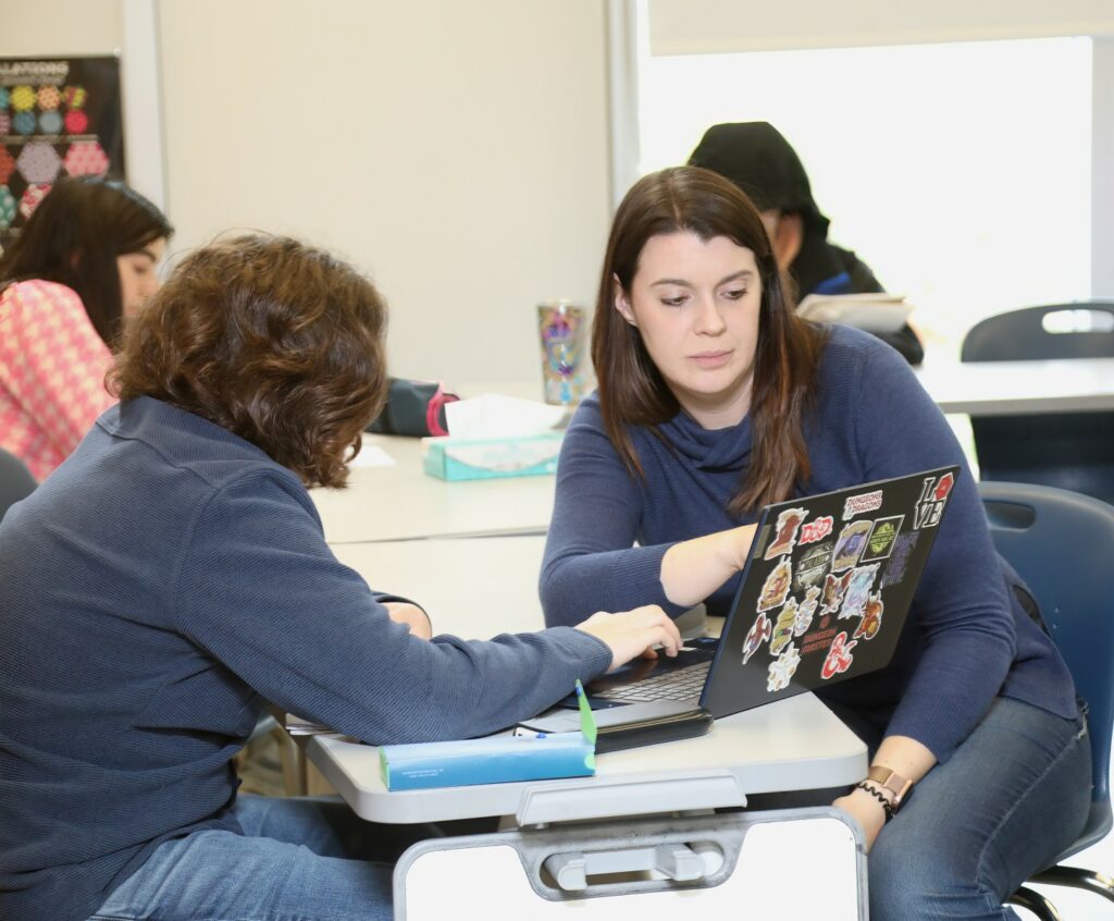 estudiantes sentados en un pupitre mirando el portátil