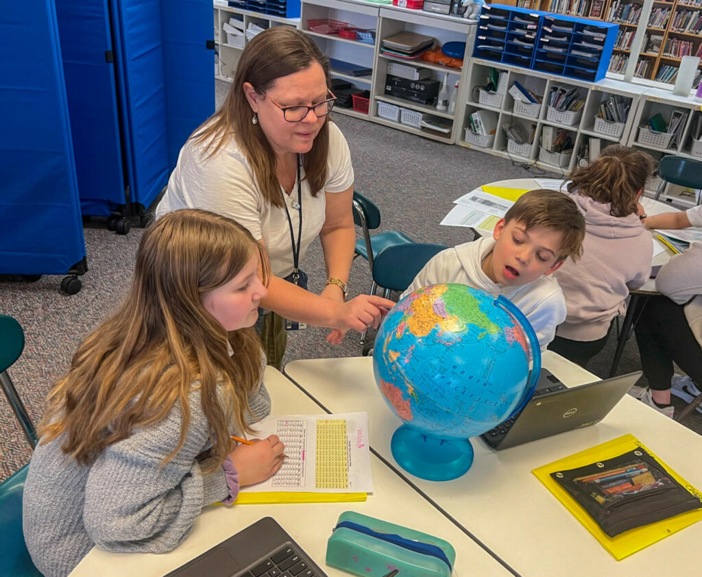 enseignant et élèves avec globe terrestre à la table