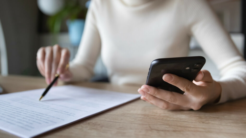 Frau mit Telefon, Stift und Papier